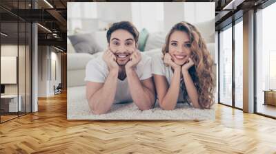 Face hairstyle hairdo bristle stubble toothy concept. Portrait of stylish trendy couple lying on floor in living room having beaming smiles looking at camera Wall mural