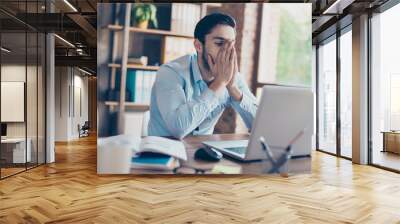 frustrated young brunet banker man is holding his face, he is upset and tired, in formal outfit at h Wall mural