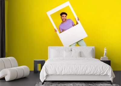 Full body cadre of young funky guy hold paper memories borders instant shooting event post instagram isolated on yellow color background Wall mural