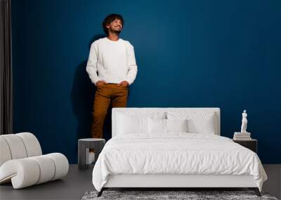 Full body length photo of young indian guy in white pullover brown pants looking empty space minded isolated on dark blue color background Wall mural