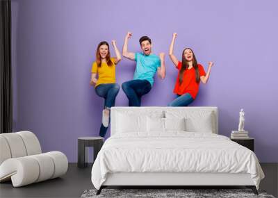 Full body length size photo of cheerful excited ecstatic positive lucky company of fellows having fun raising fists up isolated over violet background Wall mural