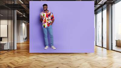 Full body photo of attractive young man hold device dressed stylish colorful clothes isolated on violet color background Wall mural