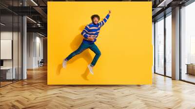 Full body photo of attractive young man hold device fly superman dressed stylish blue striped clothes isolated on yellow color background Wall mural