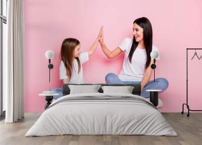 Full body photo of attractive young mom small daughter best friends sit floor crossed legs clap arms cool team wear casual white t-shirts jeans shoes isolated pastel pink color background Wall mural