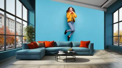 Full body photo of beautiful lady jumping high enjoy weekend playful mood warm weather wear stylish windbreaker jeans scarf sweater isolated blue color background Wall mural