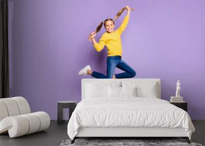 Full body photo of cheerful cute kid have fun on spring holidays jump hold pigtails wear casual style clothing sneakers isolated over violet color background Wall mural