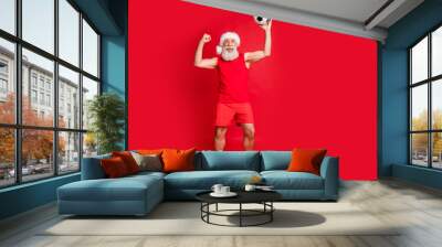 Full body photo of delighted santa claus in nicholas hat cap holding playing ball screaming yeah have goal wearing panties sports wear isolated over red background Wall mural