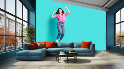 Full body photo of lovely teen lady jump winning raise fists dressed stylish pink garment isolated on cyan color background Wall mural