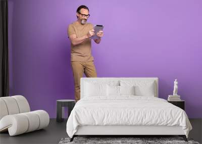 Full body photo of mature man look browse tablet app button download isolated over violet color background Wall mural