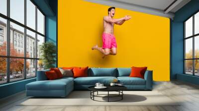 Full body profile side photo of young man happy positive smile jump swim ocean vacation isolated over yellow color background Wall mural