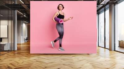 Full body profile side photo of young sportive girl happy positive smile hold mat go walk aerobic isolated over pink color background Wall mural