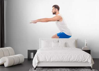 Full length, side view portrait of active, sporty, attractive person showing how it is right to make squats with straight hands, arms forward, isolated on white background Wall mural