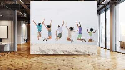 Full length back view photo of crazy overjoyed best friends jumping up spend free time near lake sea hang out together Wall mural