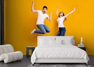 Full length body size photo funky she her he him his pair jumping high raised fists yell scream shout loud cheerleader football fans wear casual jeans denim white t-shirts isolated yellow background Wall mural