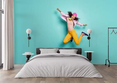 Full length body size photo of casual cheerful pretty nice free girlfriend wearing yellow trousers striped t-shirt pink cap headwear jacket flying jumping like air plane isolated teal vivid color Wall mural