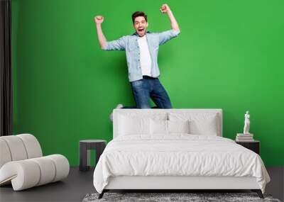 Full length body size photo of cheerful crazy ecstatic guy rejoicing with his favorite sport team having won competitions isolated jumping isolated over green vivid color background Wall mural