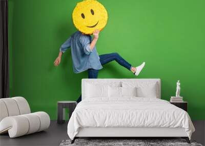 Full length body size side profile photo of man hiding face behind yellow smile isolated vivid green color background Wall mural