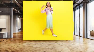 Full length body size view of attractive cheerful girl going showing heart shape isolated over bright yellow color background Wall mural