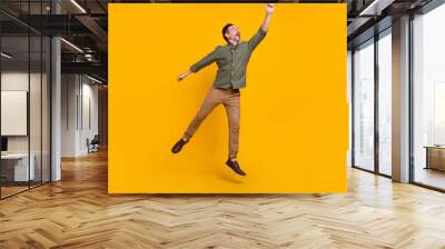 Full length body size view of attractive cheery dreamy man jumping holding copy space isolated over bright yellow color background Wall mural