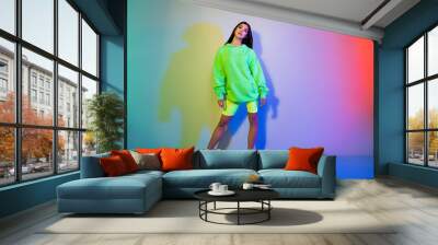 Full length body size view of attractive cool girl wearing sporty clothes posing isolated over multicolor vivid neon light background Wall mural