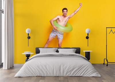 Full length body size view of attractive shirtless cheerful guy having fun wearing life buoy isolated over bright yellow color background Wall mural