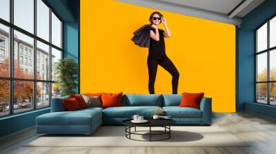 Full length body size view of attractive trendy cheerful girl carrying bags posing touching specs isolated bright yellow color background Wall mural