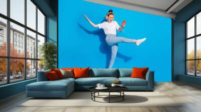 Full length body size view of nice attractive cheerful crazy girl jumping listening pop audio mp3 technology virtual connection isolated on bright vivid shine vibrant blue color background Wall mural