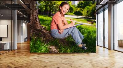 Full length photo of adorable little girl have fun outside activity sit under tree homework enjoy summer weekend pastime fresh air outdoor Wall mural