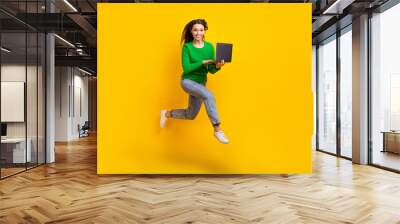 Full length photo of busy cheerful lady dressed green pullover jumping high texting modern device isolated yellow color background Wall mural