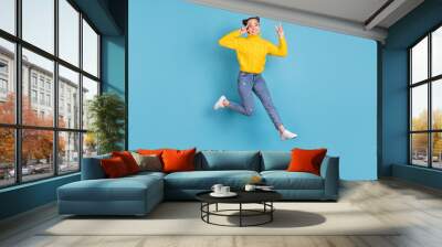 Full length photo of cheerful person jump fingers show v-sign near eye isolated on blue color background Wall mural