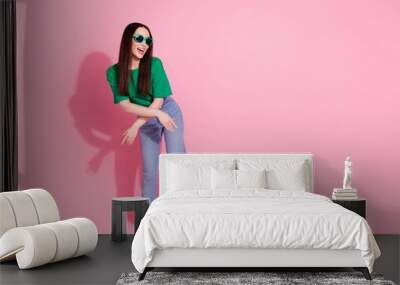 Full length photo of cheerful pretty lady dressed green t-shirt dark eyewear having fun empty space isolated pink color background Wall mural