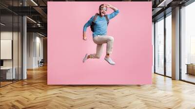 Full length photo of cute guy wear pullover glasses backpack skydive arm head looking far away isolated pink color background Wall mural