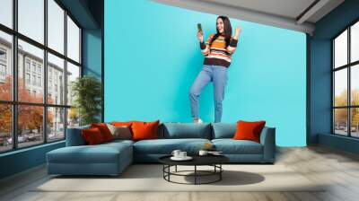 Full length photo of cute lucky lady dressed striped pullover winning game modern gadget isolated teal color background Wall mural