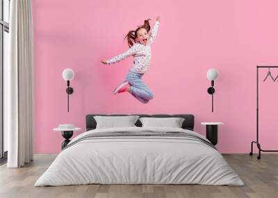 Full length photo of funky cheerful small girl wear stylish sweatshirt jeans flying near empty space isolated on pink color background Wall mural