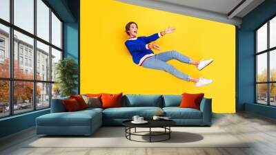 Full length photo of funky positive girl wear blue pullover falling down catching hands arms empty space isolated yellow color background Wall mural