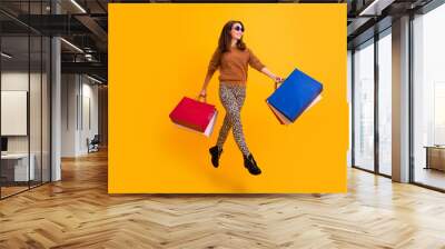 Full length photo of funny stylish lady jumping high carry many packs excited shopper wear fluffy sweater leopard trousers boots isolated yellow color background Wall mural