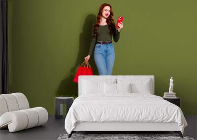 Full length photo of girlish lovely lady dressed shirt holding bargains texting modern device empty space isolated green color background Wall mural