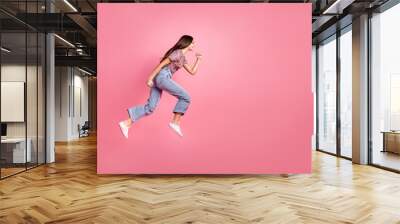 Full length photo of girlish pretty lady dressed print clothes jumping high running emtpy space isolated pink color background Wall mural