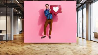 Full length photo of handsome man hold big red like notification icon recommend you subscribe his blog isolated on pink color background Wall mural