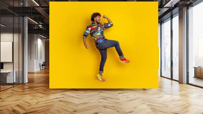 Full length photo of handsome young male celebrate raise fists dressed stylish colorful garment isolated on yellow color background Wall mural