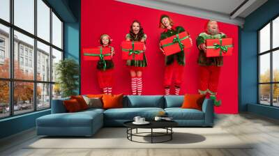 Full length photo of hooray santa assistants people give gifts wear masquerade costumes isolated on red color background Wall mural