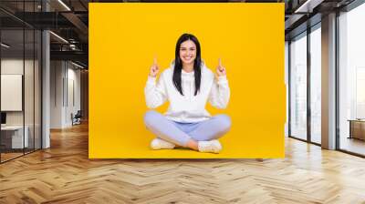 Full length photo of lady sit legs crossed point hand empty space black friday ads isolated over shine yellow color background Wall mural