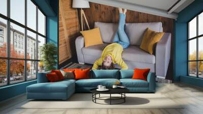 Full length photo of lovely young lady lying sofa upside down winning dressed yellow sweater spend pastime spacious house indoors room Wall mural