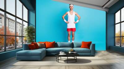 Full length photo of sporty man hold hand waist wear white singlet gumshoes isolated over blue color background Wall mural