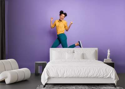 Full length profile photo of pretty dark skin lady jumping high celebrating favorite team victory wear casual yellow shirt trousers isolated purple color background Wall mural