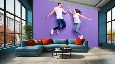 Full length profile side photo of cheerful two people freelancer jump win discount clap high five gesture wear white t-shirt denim jeans gumshoes isolated over violet color background Wall mural