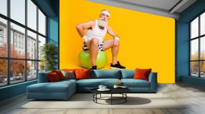 Full size photo of aged guy sitting on green fit ball after squats set making little break sportswear tank-top shorts sweatband sneakers isolated yellow color background Wall mural