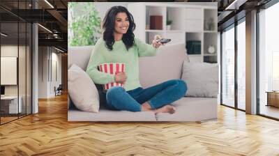 Full size photo of happy joyful young dark skin woman switch channel hold pop corn weekend sit couch indoors inside house Wall mural