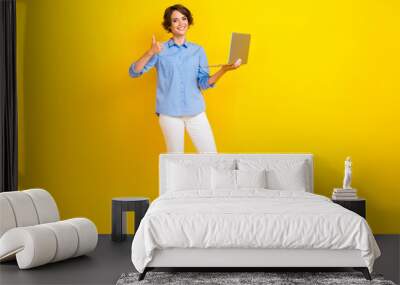 Full size photo of lovely positive woman with bob hairdo dressed white pants showing like hold laptop isolated on yellow color background Wall mural