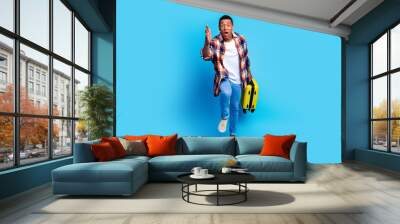 Full size photo of nice young man suitcase running raise arm catch wear shirt isolated on blue color background Wall mural